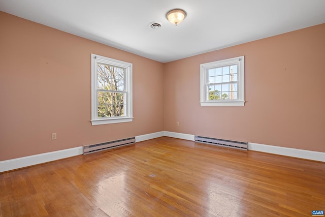 spare room featuring baseboard heating, visible vents, and a healthy amount of sunlight