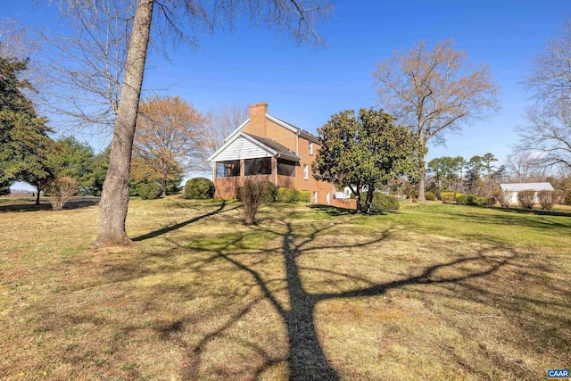 view of front of house with a front lawn, a chimney, and a sunroom