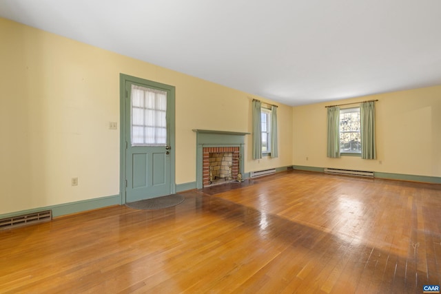 unfurnished living room featuring a fireplace, visible vents, a baseboard heating unit, and hardwood / wood-style flooring