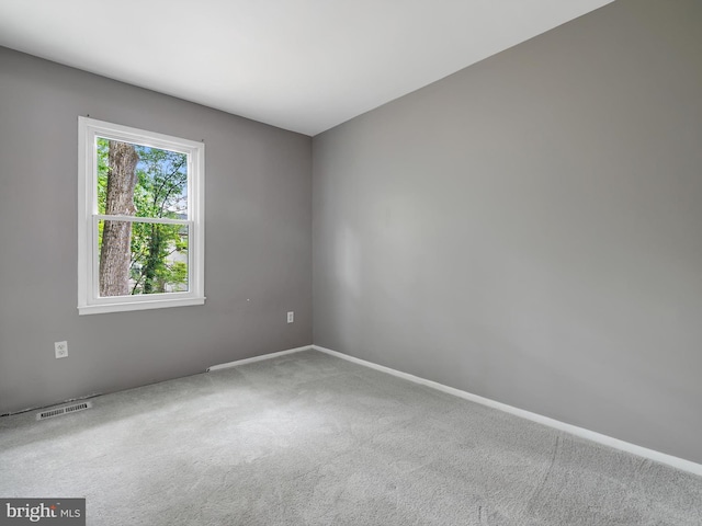 empty room featuring carpet and baseboards
