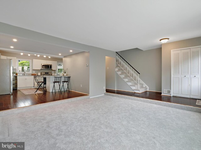 living area featuring recessed lighting, stairway, dark colored carpet, baseboards, and dark wood-style flooring