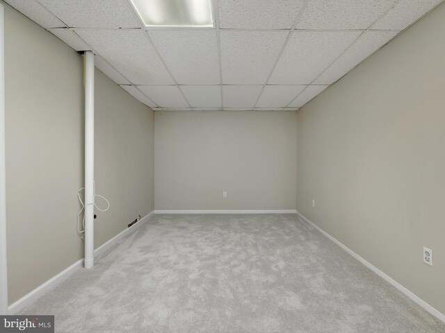 finished below grade area with a drop ceiling, carpet floors, and baseboards