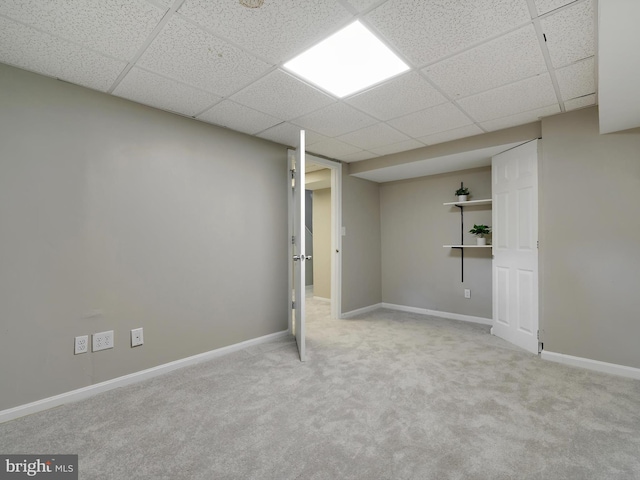 finished basement featuring a drop ceiling, carpet flooring, and baseboards