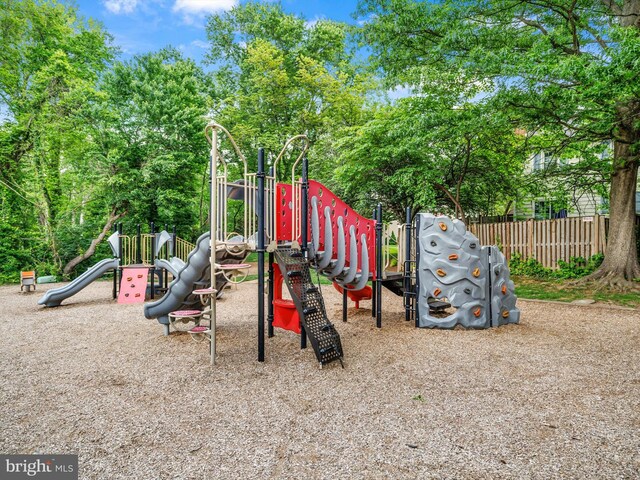community play area featuring fence and view of scattered trees