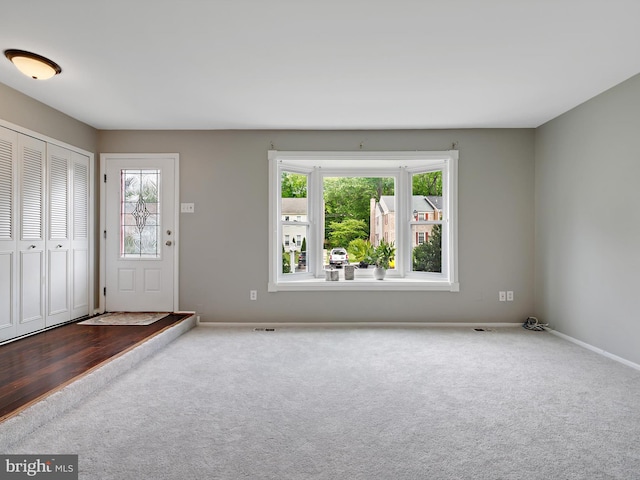 carpeted foyer featuring plenty of natural light and baseboards