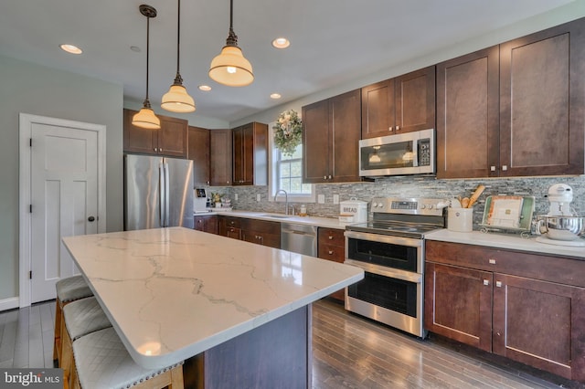 kitchen featuring light stone counters, tasteful backsplash, appliances with stainless steel finishes, and dark wood-style flooring