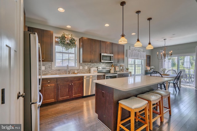 kitchen with stainless steel appliances, a sink, backsplash, a breakfast bar, and wood-type flooring