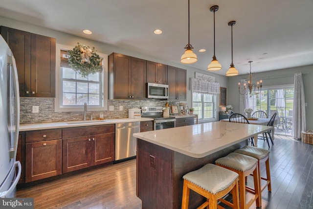 kitchen featuring stainless steel appliances, a breakfast bar, a sink, a center island, and tasteful backsplash