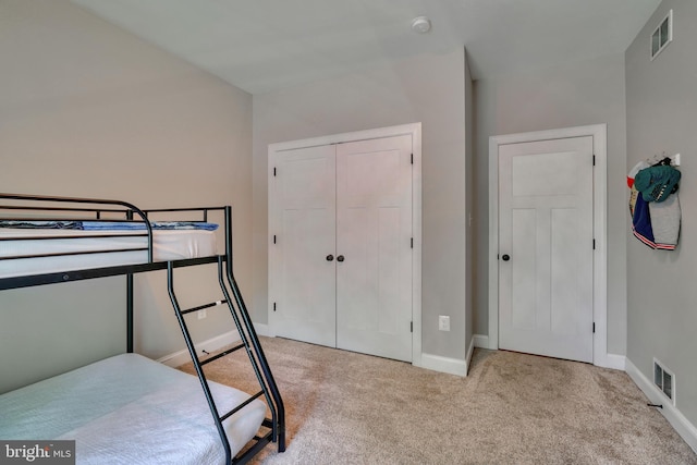 carpeted bedroom with a closet, visible vents, and baseboards