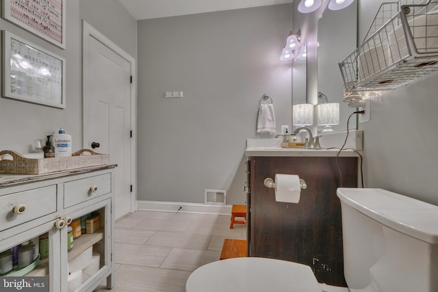 bathroom with baseboards, visible vents, vanity, and toilet