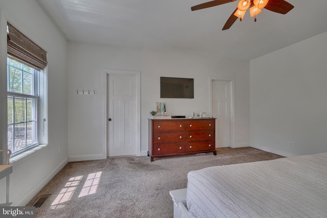 carpeted bedroom with baseboards, a ceiling fan, and visible vents