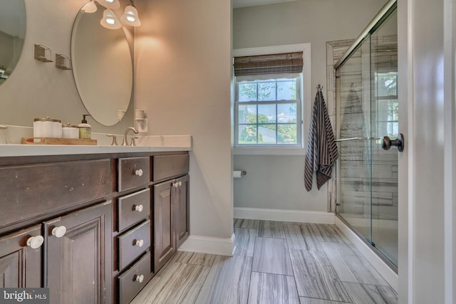 full bath featuring a tile shower, baseboards, and vanity