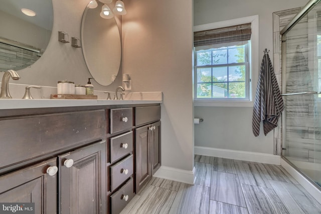 full bath featuring baseboards, vanity, and a stall shower