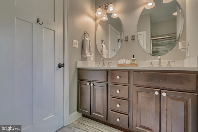 full bathroom featuring double vanity, baseboards, and a sink