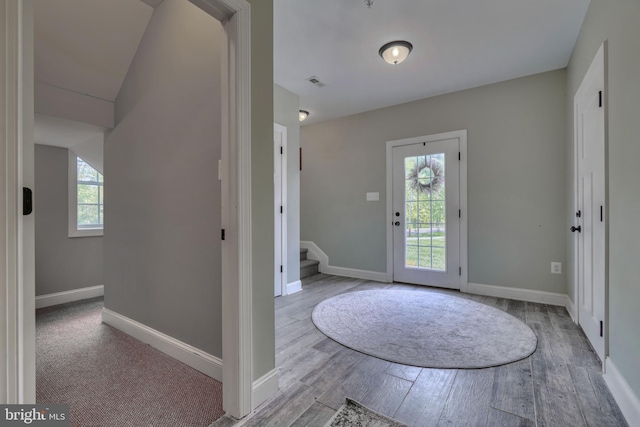 foyer featuring wood finished floors, baseboards, and stairway