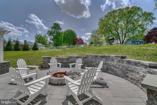 view of patio featuring a fire pit, a playground, and fence