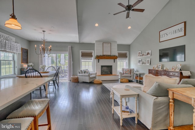 living area featuring dark wood-style floors, high vaulted ceiling, recessed lighting, and ceiling fan with notable chandelier