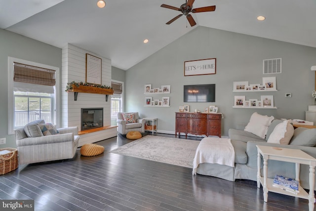 living area featuring wood finished floors, visible vents, a fireplace, high vaulted ceiling, and ceiling fan