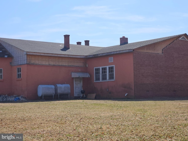 rear view of house featuring a yard, heating fuel, crawl space, and a chimney