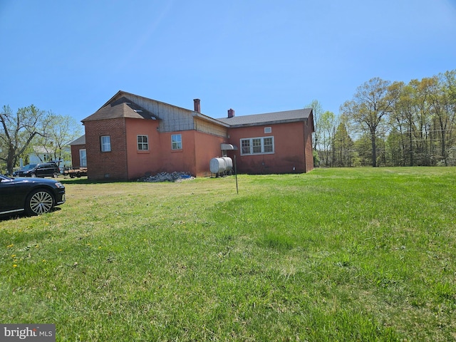 view of home's exterior featuring heating fuel, a chimney, crawl space, brick siding, and a yard