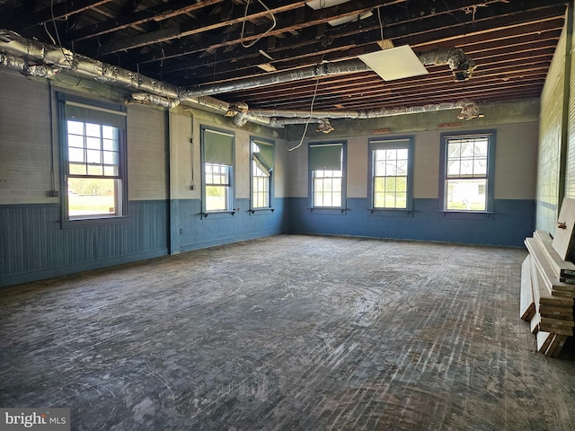 empty room featuring a wainscoted wall and a healthy amount of sunlight