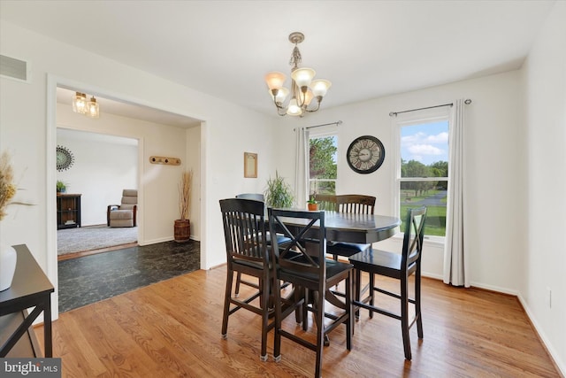 dining space featuring visible vents, baseboards, wood finished floors, and an inviting chandelier