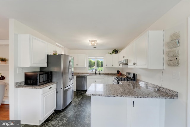 kitchen featuring a peninsula, light stone countertops, under cabinet range hood, white cabinets, and stainless steel appliances