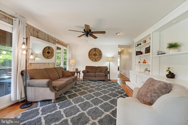 living area with baseboards, built in features, ceiling fan, and wood finished floors