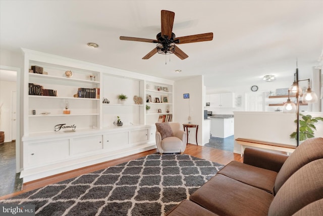 living area with built in features, ceiling fan, and wood finished floors
