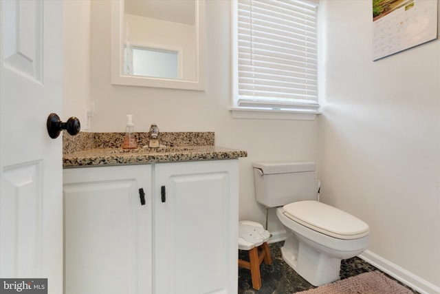 bathroom featuring baseboards, vanity, and toilet
