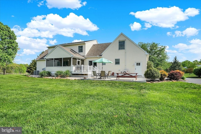 rear view of property featuring a yard, a sunroom, central AC, and a patio area
