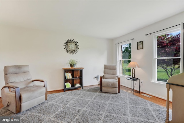 sitting room featuring visible vents, baseboards, wood finished floors, and a wealth of natural light