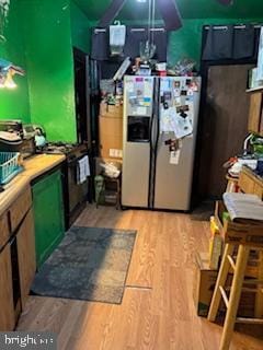 2309 Lauretta Ave, Baltimore, MD 21223 - kitchen featuring stainless steel fridge with ice dispenser, light wood-type flooring, black gas range, and green cabinetry