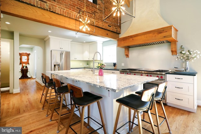 451 E Hamilton Ave, State College, PA 16801 - kitchen with white cabinets, appliances with stainless steel finishes, light wood finished floors, a kitchen island with sink, and custom range hood