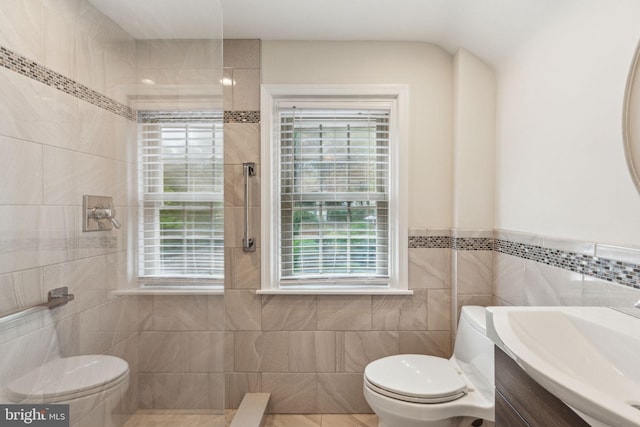 bathroom with tile patterned floors, tile walls, toilet, and vanity