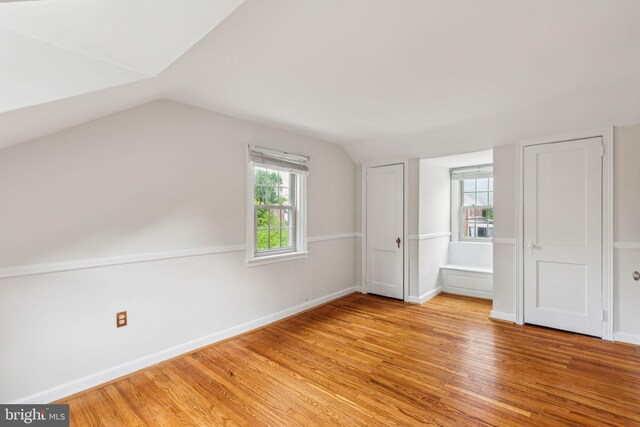 bonus room with lofted ceiling, baseboards, and light wood-style floors