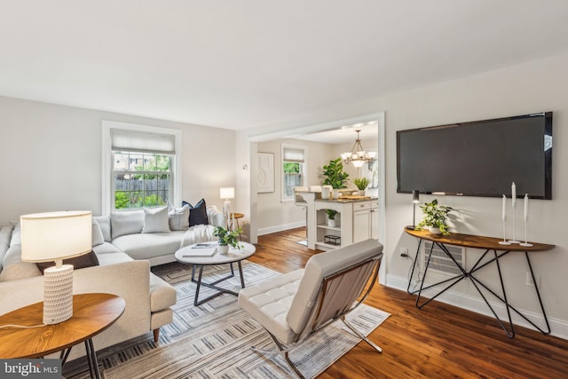 living room featuring baseboards, a chandelier, and wood finished floors