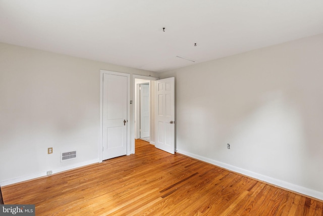 unfurnished room with light wood finished floors, visible vents, and baseboards