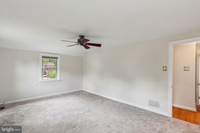 carpeted empty room featuring visible vents, baseboards, and ceiling fan