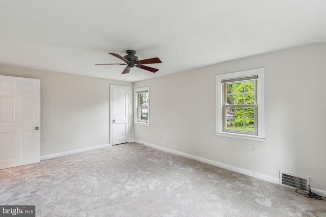 spare room featuring carpet, baseboards, a ceiling fan, and visible vents