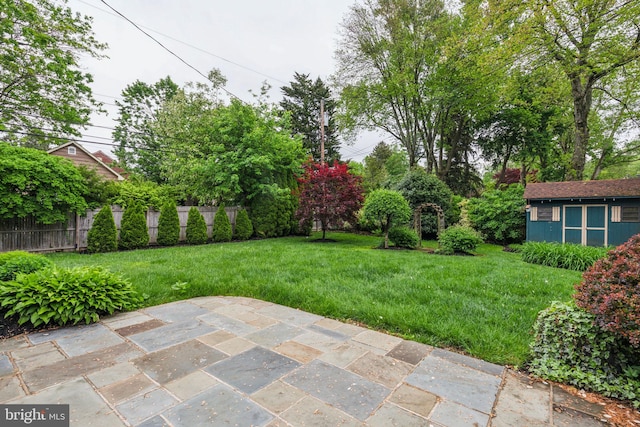 view of yard featuring a patio area, an outdoor structure, and fence
