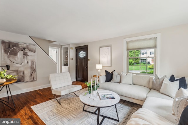 living room featuring wood finished floors, baseboards, and stairs