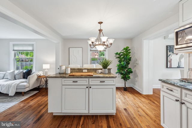 kitchen featuring a notable chandelier, light wood-type flooring, baseboards, and white cabinets