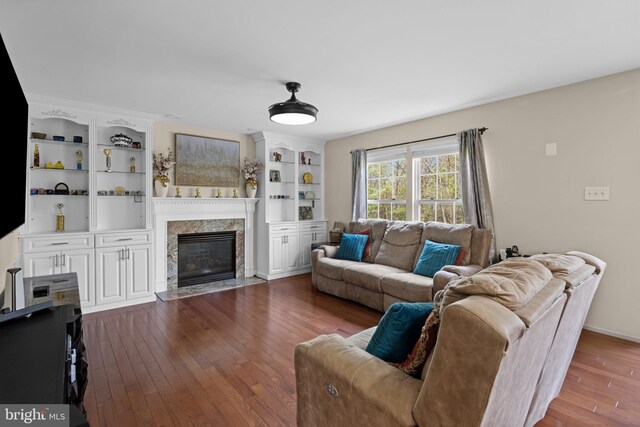 living area featuring a high end fireplace, baseboards, and dark wood-type flooring