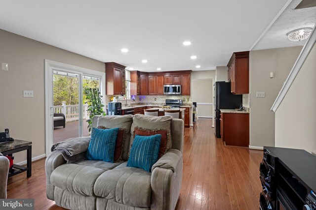 living room with wood-type flooring, recessed lighting, and baseboards