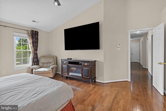 bedroom with baseboards, visible vents, wood-type flooring, and vaulted ceiling