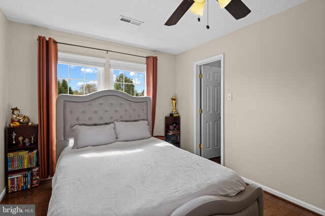 bedroom featuring wood finished floors, visible vents, a ceiling fan, and baseboards