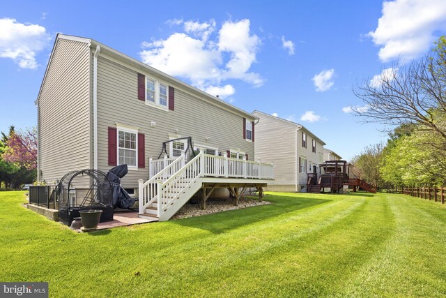 back of property featuring a lawn, a wooden deck, and stairs