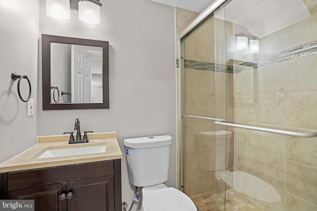 bathroom featuring a shower stall, toilet, and vanity