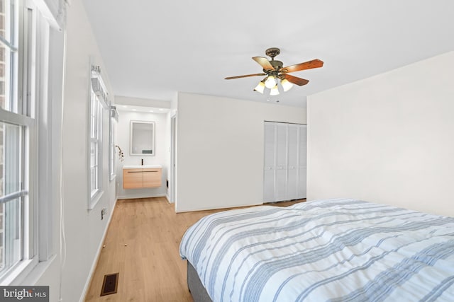 bedroom with light wood-style flooring, baseboards, visible vents, a ceiling fan, and a closet